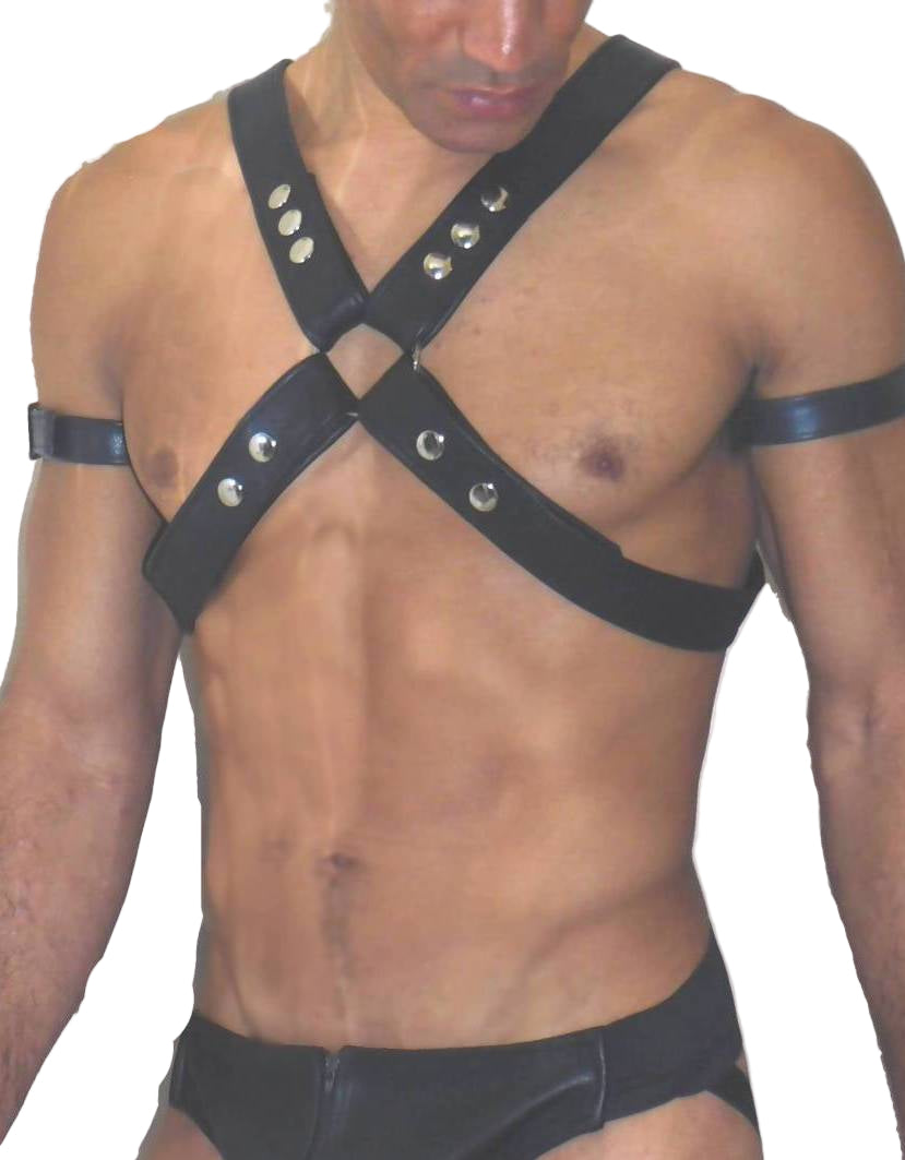 Man wearing a black leather harness with studs on a plain background