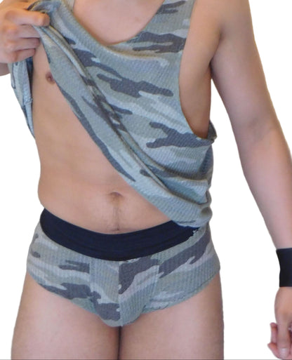 Person wearing a camouflage tank top and shorts against a white background